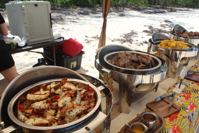Buffet chafing dishes laid out at a beach set up for a charter group