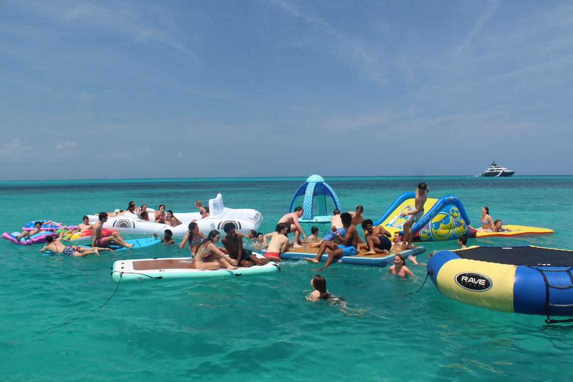 A large group of guests on inflatables in the water beside the 80ft Atlantis II catamaran