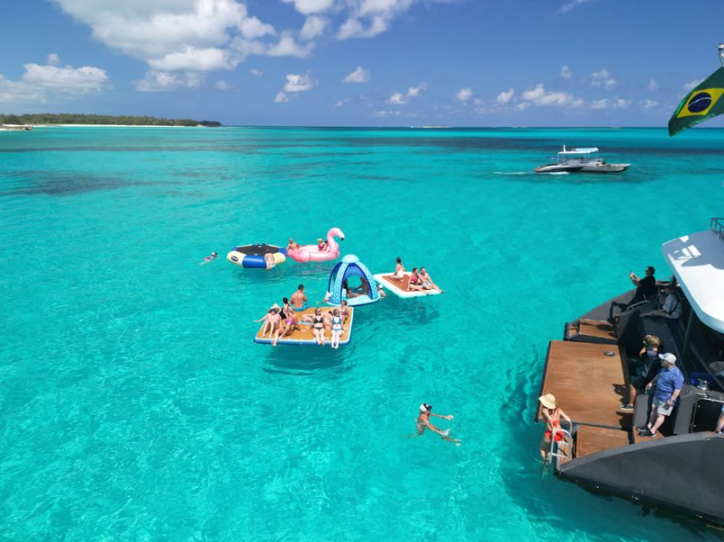 Guests on floating mats beside the boarding platform of the 80ft Atlantis II catamaran