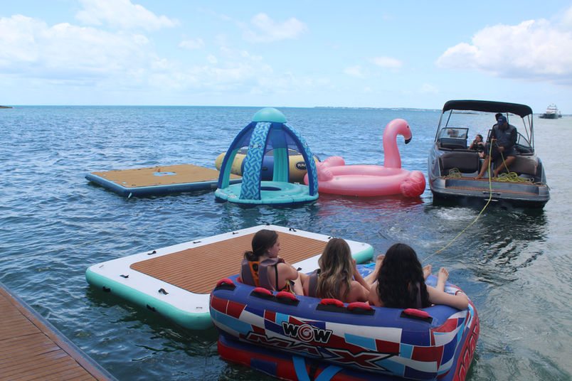 Floating islands and a towable tube set out in the water beside the 80ft Atlantis II catamaran