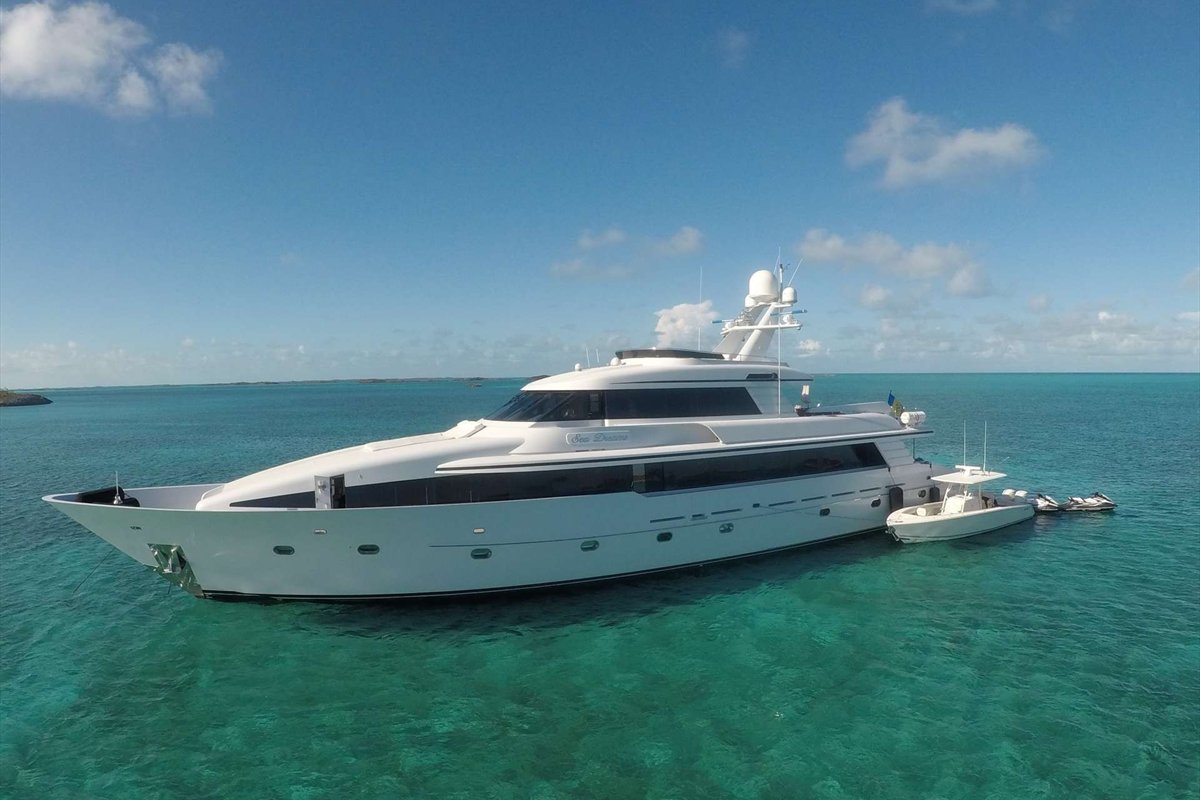 Luxury motor yacht at anchor in clear Bahamian water with its tender alongside