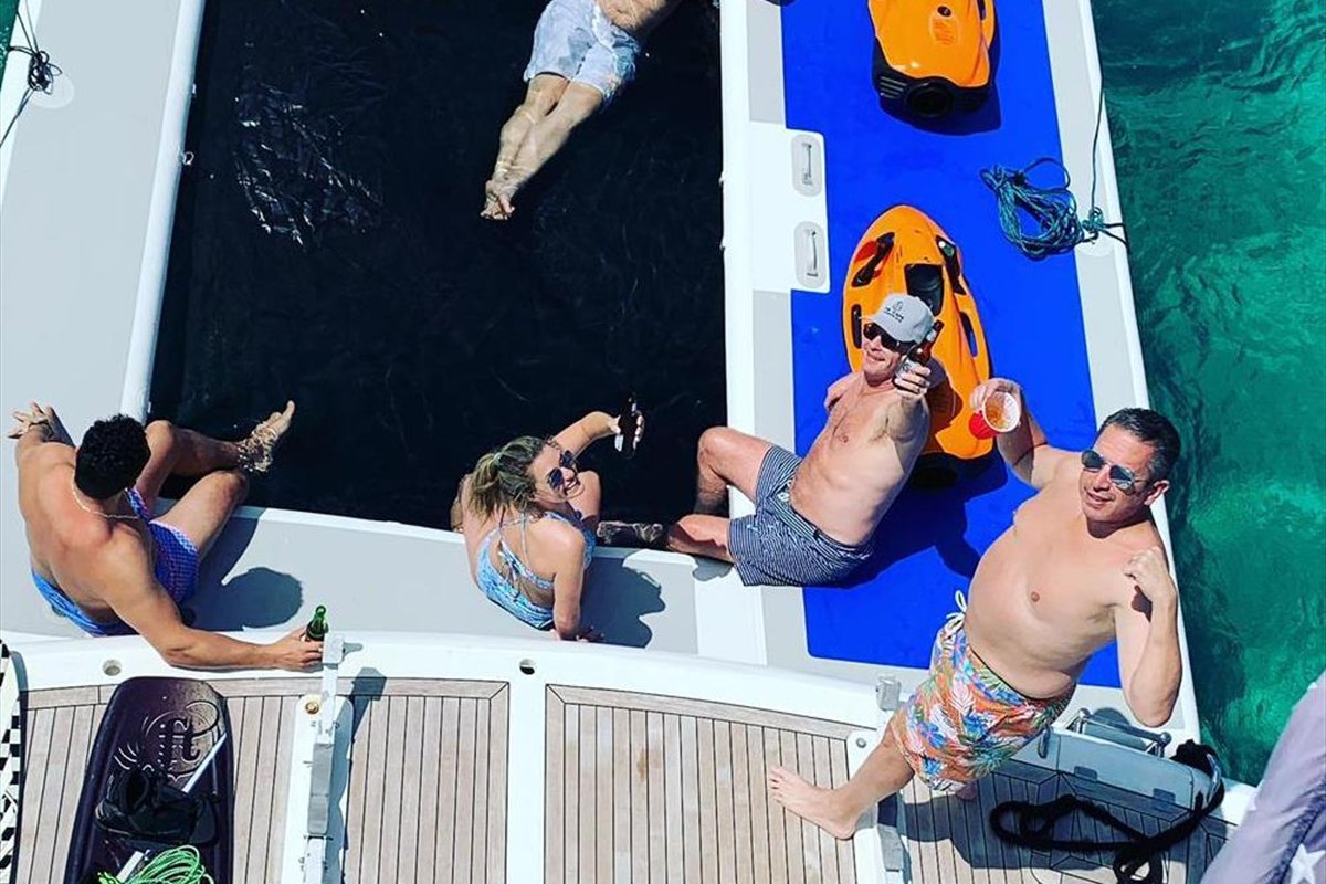 Guests relaxing on the swim platform of a charter yacht with inflatables in the water