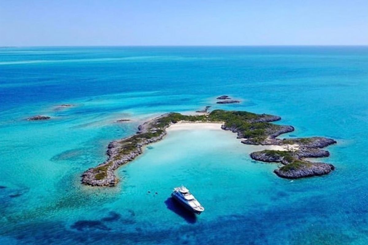 Aerial view of a Bahamian cay with boats anchored in turquoise shallows