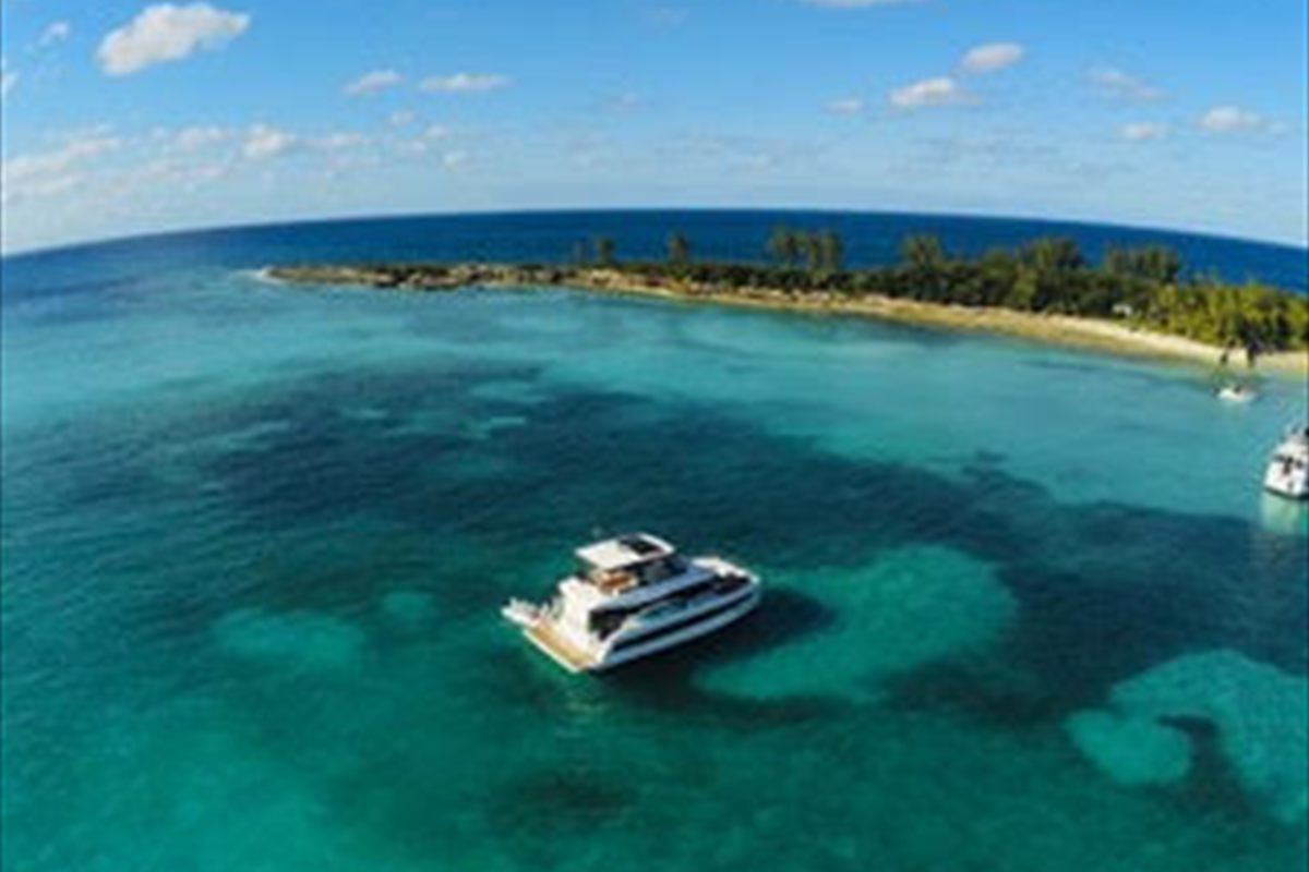 Charter catamaran anchored over a reef patch in clear Bahamian water