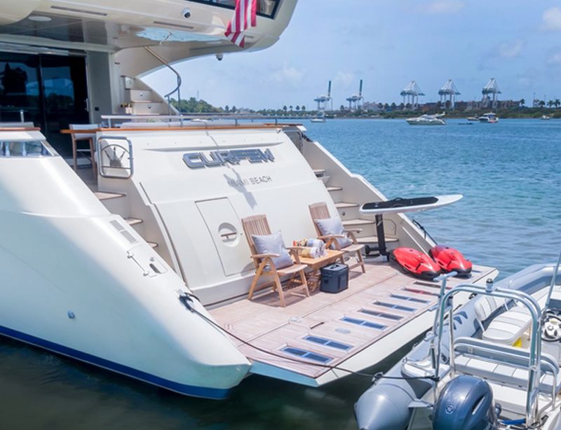 Teak aft deck and swim platform of the 100 Dominator with seating and kayaks