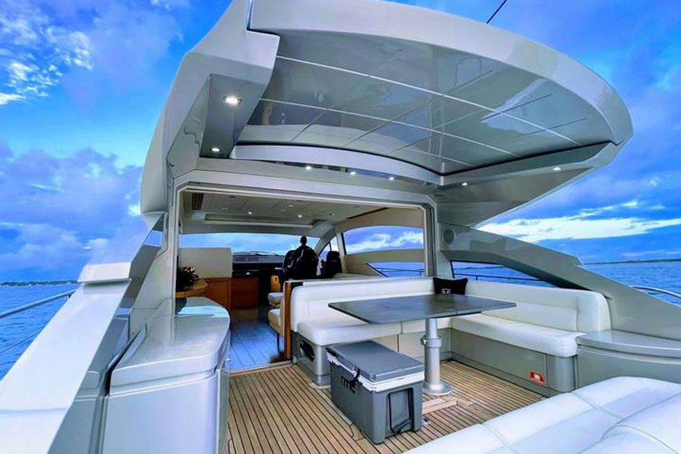 Shaded aft cockpit of the 64 Pershing with a dining table and teak decking
