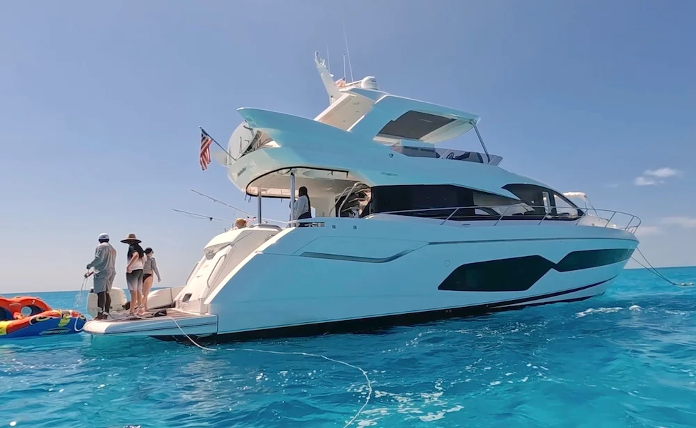 The 68 Sunseeker Manhattan at anchor in bright turquoise water with guests on her swim platform