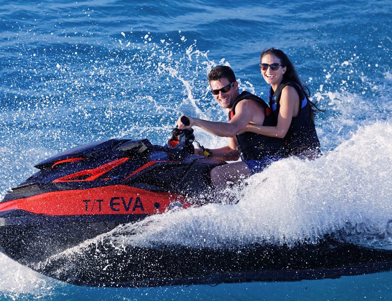 Two guests riding the yacht tender jet ski across open water