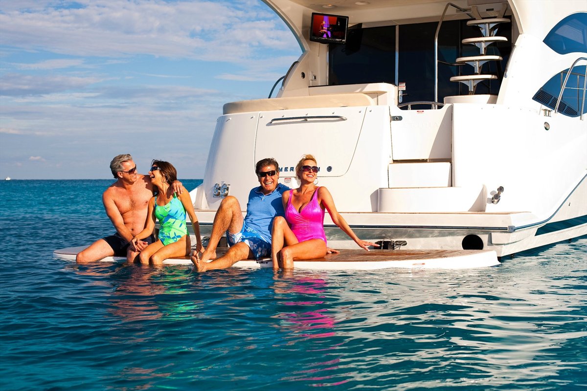 Four friends relaxing together on the swim platform of a charter yacht