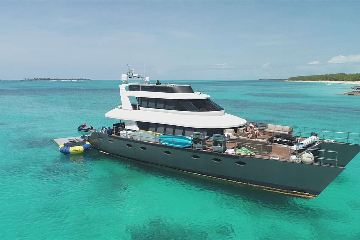 Large motor yacht lying at anchor in clear turquoise water in the Bahamas
